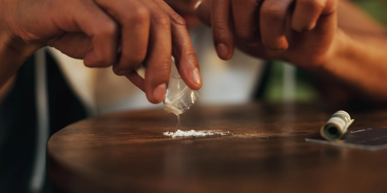 Een close-upfoto voor de pagina over verslaving, waarop te zien is hoe cocaïne op een tafel wordt klaargemaakt, waarmee de realiteit en de risico’s van verslaving worden weergegeven.