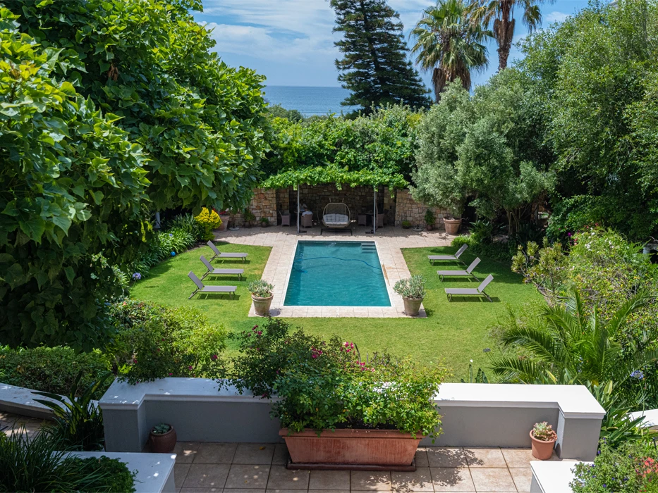 Rehab centre terrace, overlooking the garden poo, trees surrounding the garden and a view of the ocean at the far end. 