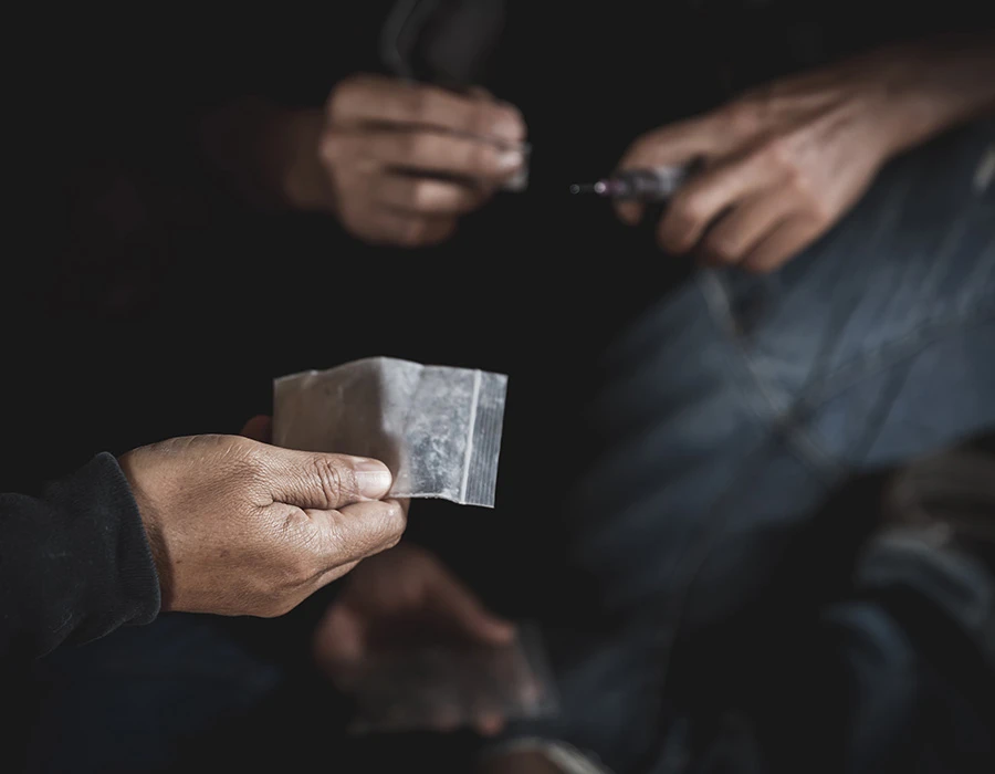 Person holding a small bag of cocaine during a drug transaction.