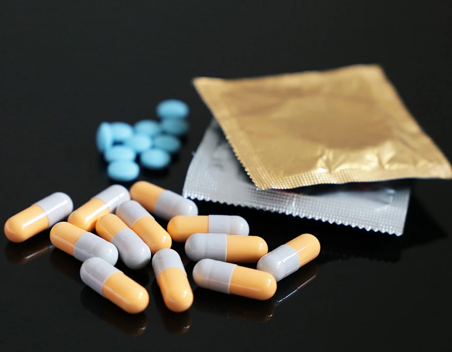 Capsules en condooms op tafel, verbonden met het gebruik van drugs tijdens chemsex.
