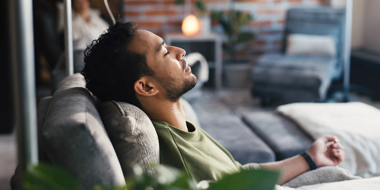 Calm man resting on a sofa with eyes closed, illustrating ketamine addiction treatment.