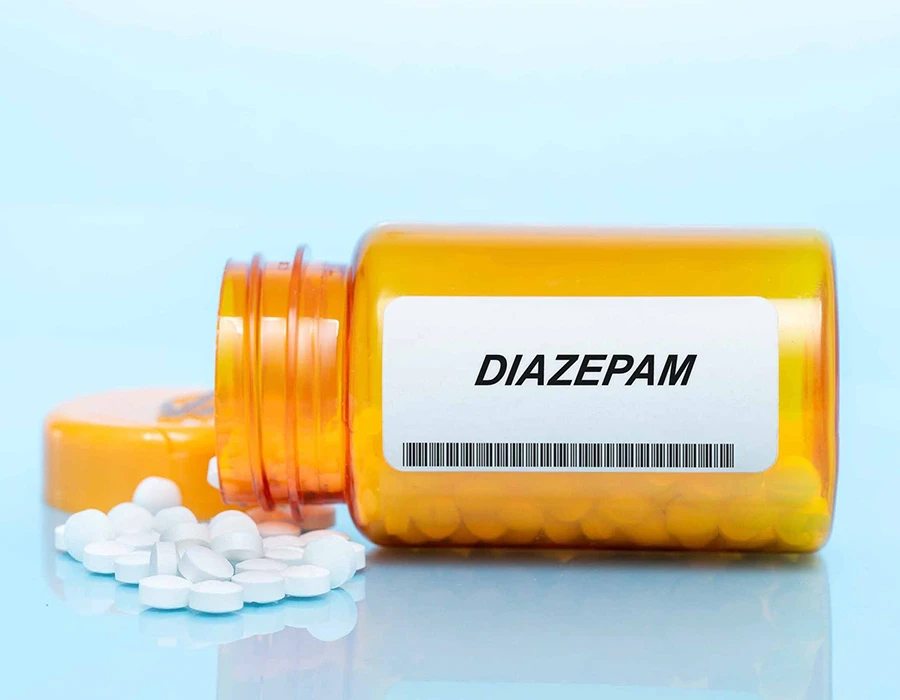 Potje met diazepam tabletten omgevallen met witte pillen ernaast op tafel.
