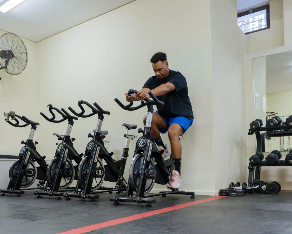 Man traint op spinningfiets in de fitnessruimte van afkickkliniek Zuid-Afrika.