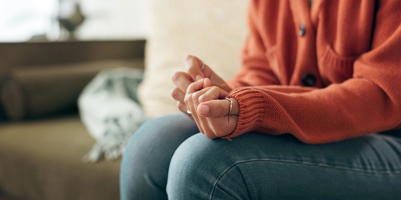 Close-up of a woman nervously fidgeting with her hands, reflecting inner tension, emotional distress and the lasting effects trauma can have on your wellbeing.