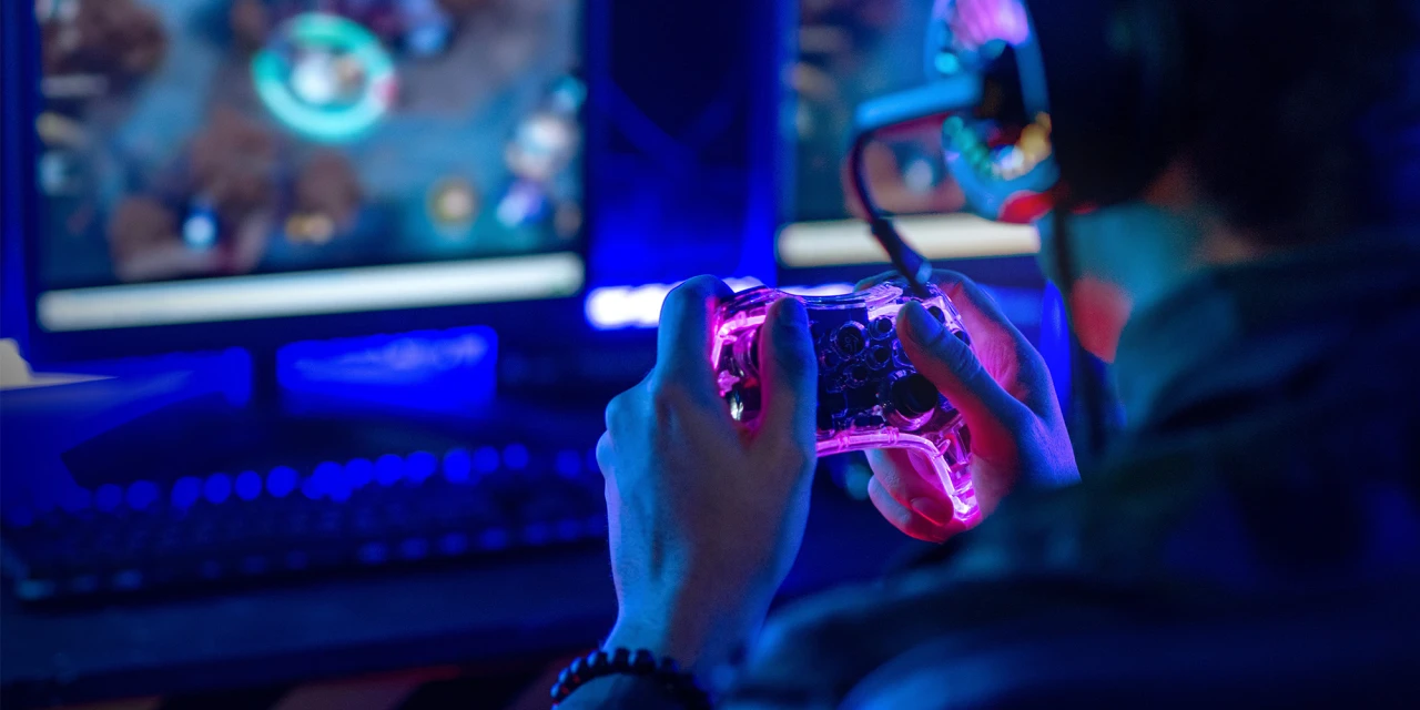 Playing video games on his TV with a controller.
