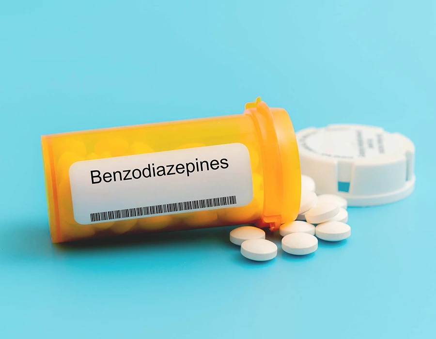 Benzodiazepine pills spilled from a prescription bottle.