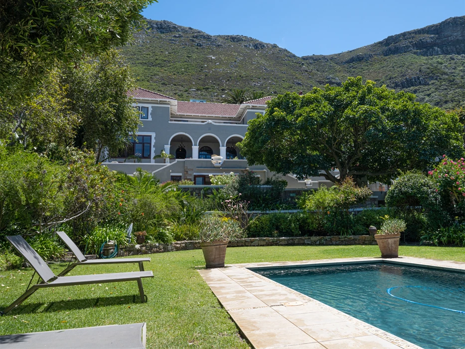 Garden at the swimming pool, surrounded by deck chairs and the rehab centre and green hills at the background.