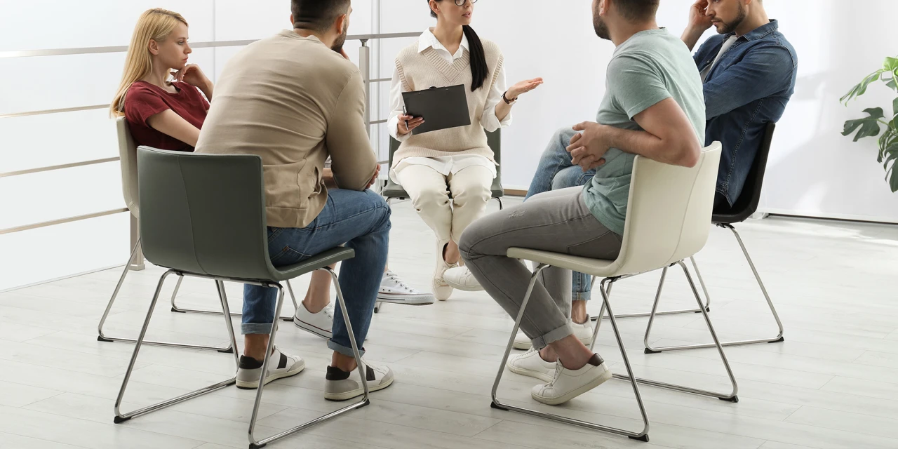 A therapist leads a group discussion at a rehabilitation centre, where people work together on recovery, emotional healing and long-term personal growth.
