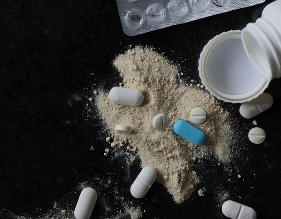 Pills spilling from a bottle beside an empty blister pack, illustrating codeine addiction.