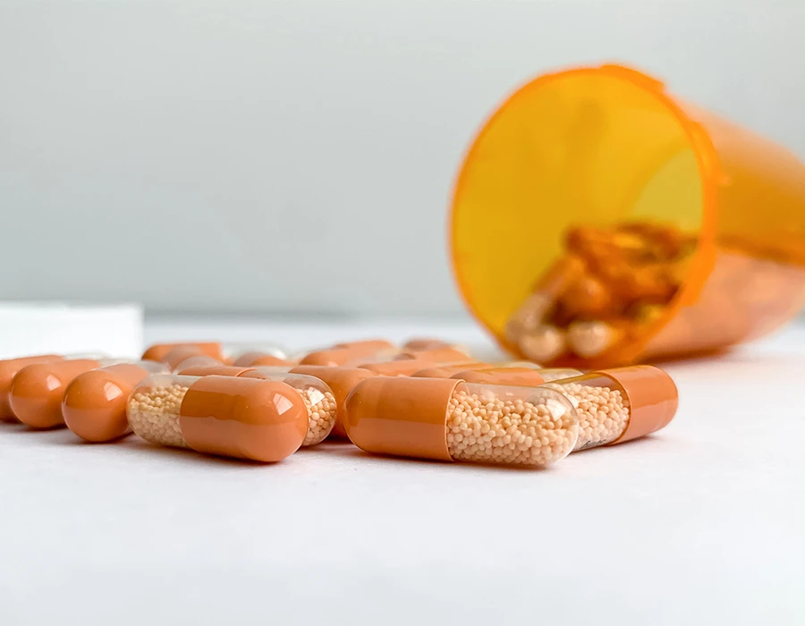 Orange capsules with beads spilling from a prescription bottle, illustrating Adderall addiction.