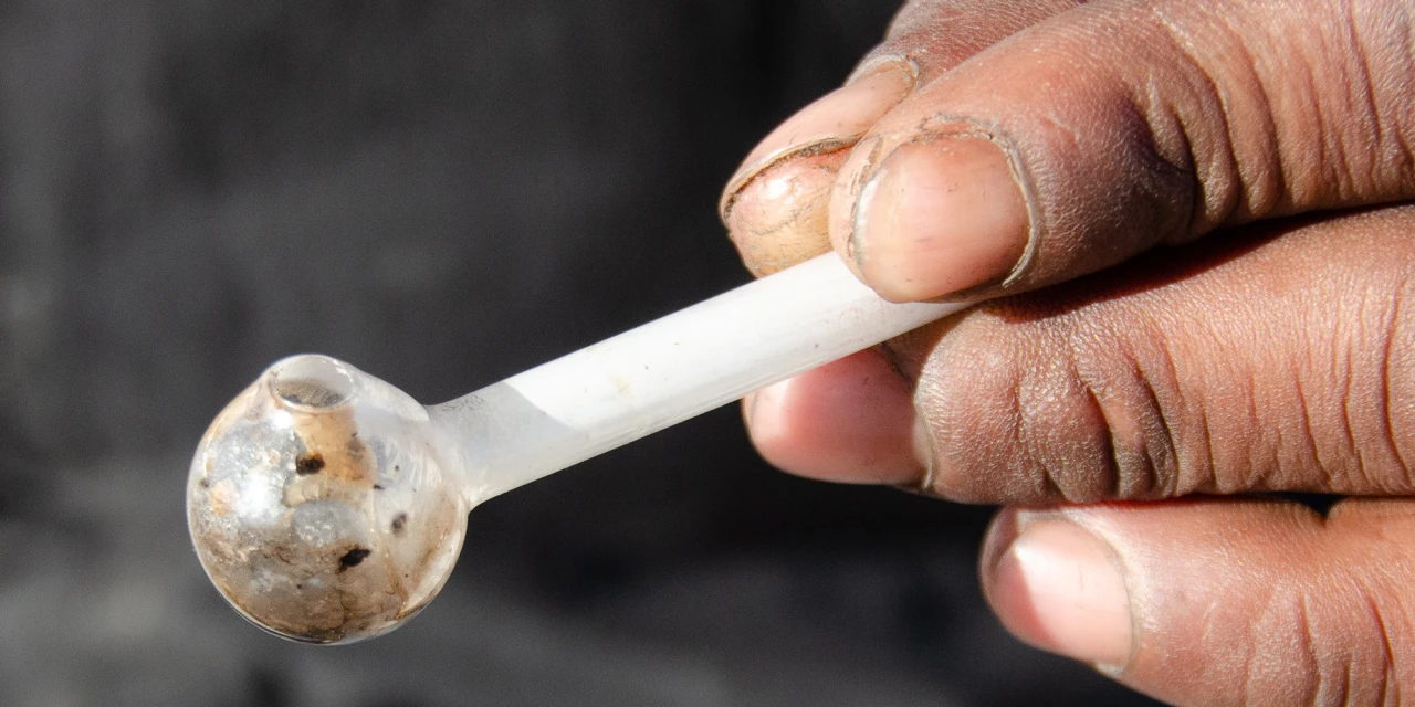 A close-up of someone holding a used meth pipe, reflecting the harmful reality and physical impact of crystal meth addiction.