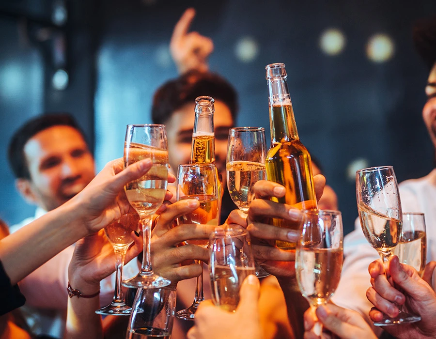 Groep vrienden proost met drankjes tijdens een avond uit waar bingedrinken centraal staat.
