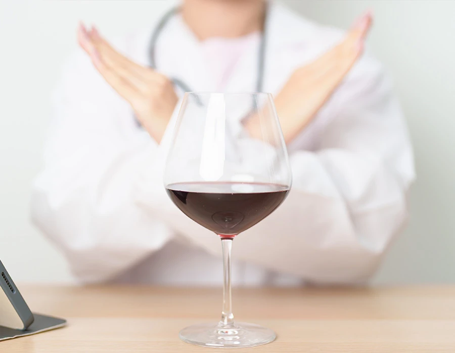 Doctor refusing a glass of red wine, illustrating alcohol-related liver disease.