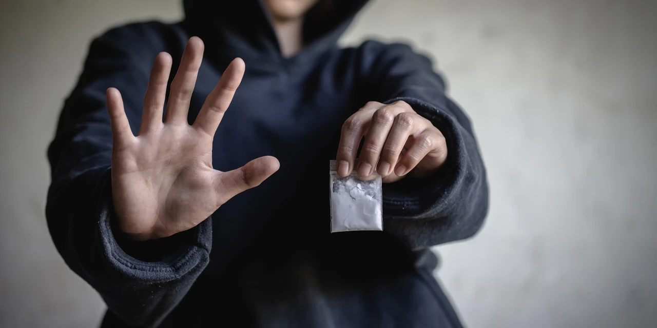 Person refusing cocaine with a stop gesture, symbolizing recovery from addiction.
