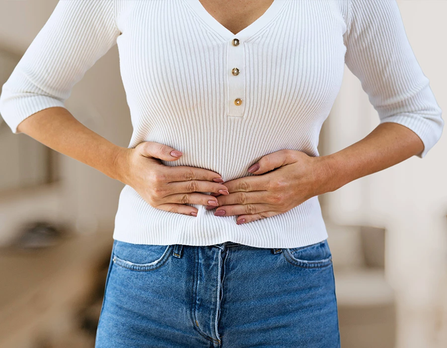 Woman holding her abdomen due to abdominal pain linked to liver disease.
