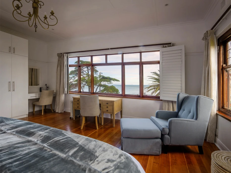 Rehab centre private room with blue armchair, writing desk and ocean view. 