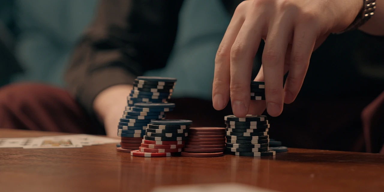 A close-up image of poker chips being stacked during a card game, reflecting behaviours commonly associated with gambling addiction.